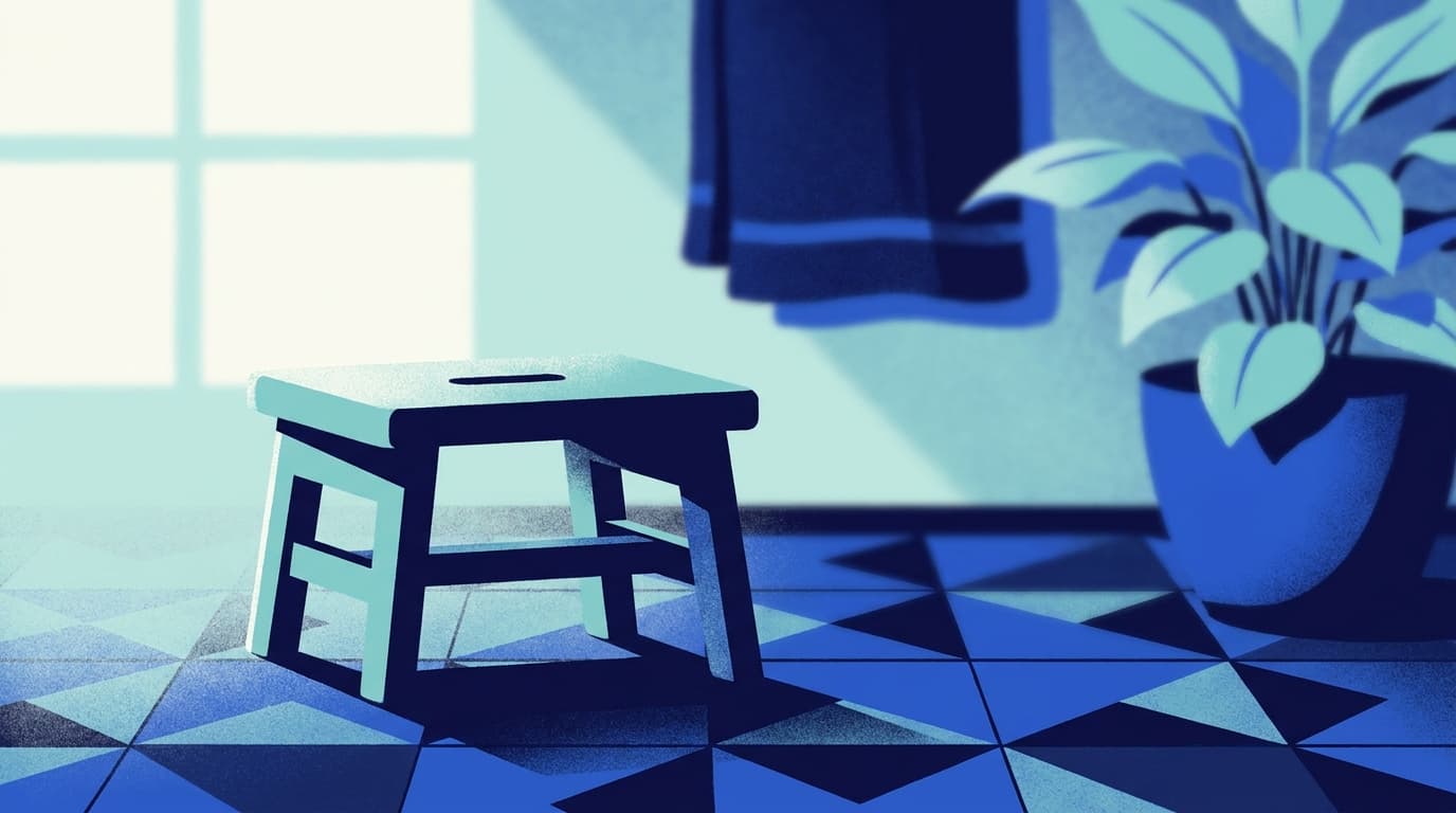 Un petit tabouret en bois posé devant une salle de bains sobre, lumière douce