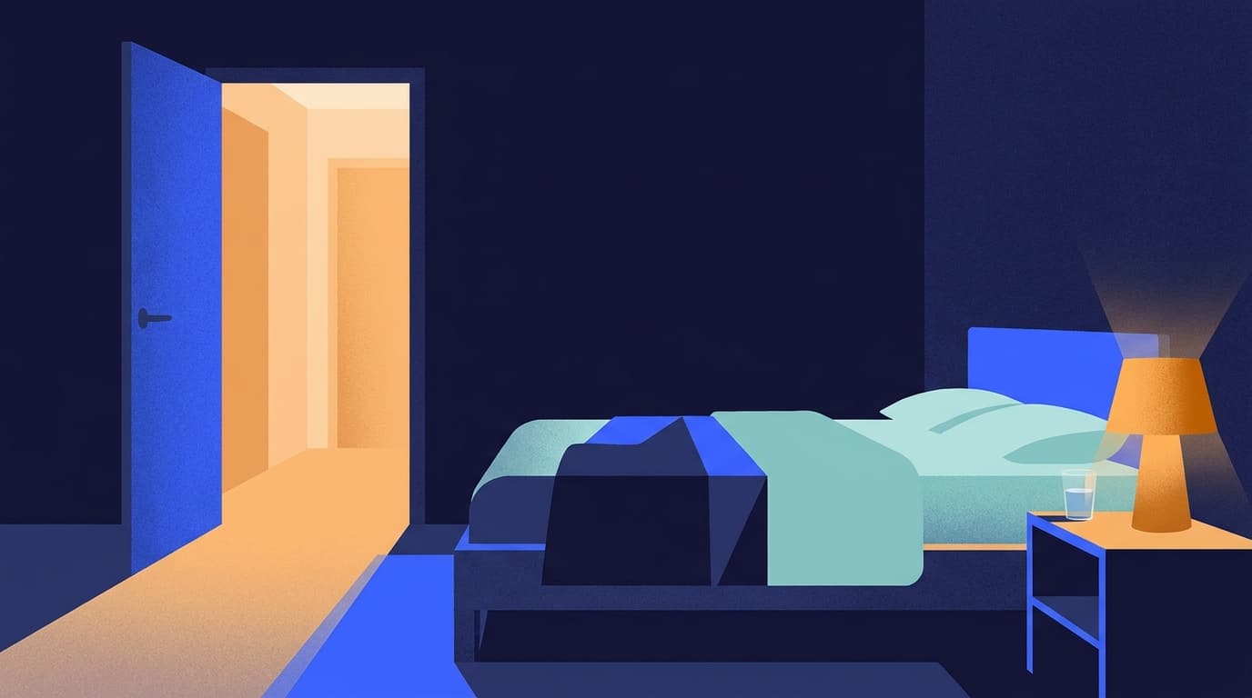 A dimly lit bedroom at night with a small lamp on a bedside table and a hallway light left on